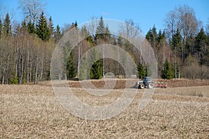 Tractor plows the earth near the forest photo