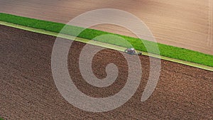 tractor plows a field from above