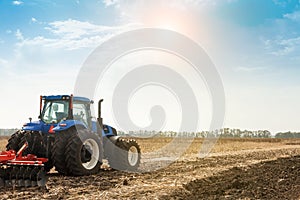 The tractor plows the field, cultivates the soil for sowing grain. The concept of agriculture photo