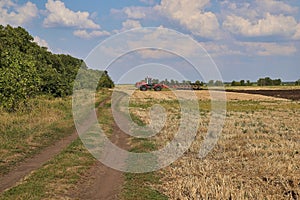 Tractor plows field, cultivators soil for sowing