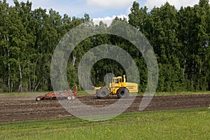 Tractor plows a field, harrows, cultivates the soil for sowing. The concept of agriculture and agricultural machinery