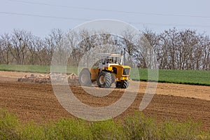 A tractor plows a field with seedbed cultivator in early spring