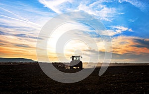 Tractor plows a field in the spring accompanied by rooks Tractor