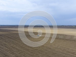 The tractor plows the field. Under sowing, the soil is loosened on the field.