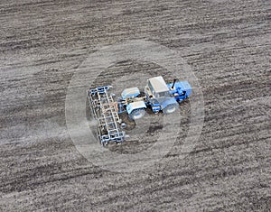 The tractor plows the field. Under sowing, the soil is loosened on the field.