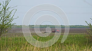 Tractor plows or harrows the ground on the field