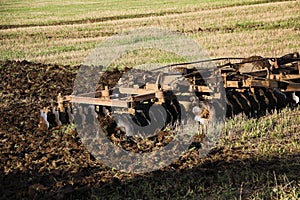 Tractor plows and harrows  land in  large field on  sunny spring day. preparing  soil for planting crops, plowing  soil with