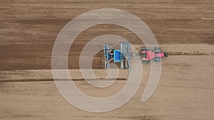 Tractor plows land and seeder plants seeds of wheat crops in agricultural field