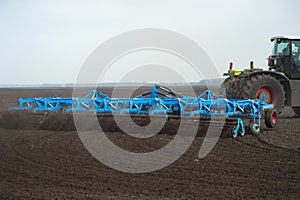 tractor preparing land with seedbed cultivator at spring farm field
