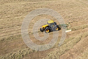 Tractor raking cut hay in field