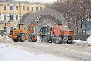 Tractor removing snow from the street in big trucks