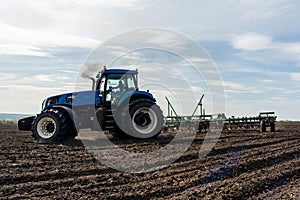 A tractor with seedbed cultivator ploughs field on morning