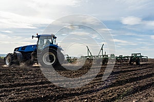 A tractor with seedbed cultivator ploughs field on morning