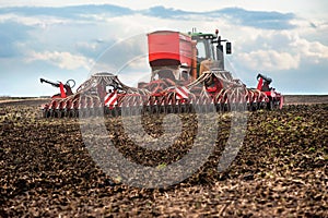 tractor with seeder in a plowed field, apply fertilizer, sowing time