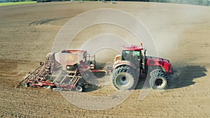 Tractor with a seeder sows grain or seeds of wheat or corn, works on field. Agricultural, mechanized sowing. Hard rural