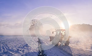 Tractor silhouette through fog, on snowy field