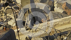 Tractor smashes a concrete block at the ruins of the building.