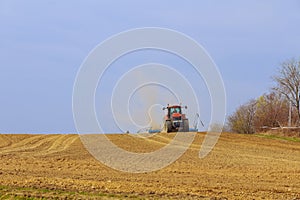 The tractor sows the field with grain, the dust has risen to the top.