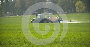 Tractor spray fertilize on field with chemicals in agriculture field.
