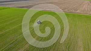 Tractor spray fertilize on field with chemicals in crops of wheat nad barley on edge of field