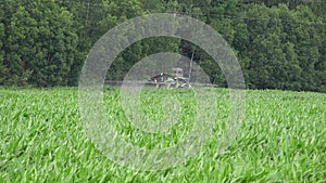 Tractor spray fertilize maize corn field with pesticide near forest. 4K