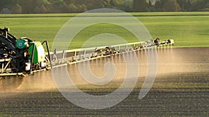Tractor spray fertilize wheat field with sprayer. Handheld slow motion follow