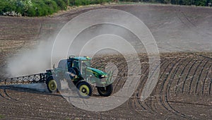 Tractor spray fertilizer spraying pesticides on green field, agriculture background concept