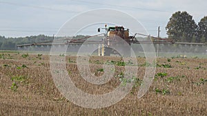 Tractor spray stubble field with herbicide chemicals in autumn