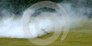 Tractor spraying field, in cloud of pesticide/ lime