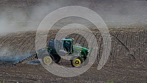 Tractor spraying pesticides on vegetable field with sprayer at spring