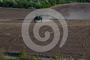 Tractor spraying pesticides on vegetable field with sprayer at spring