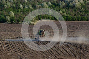 Tractor spraying pesticides on vegetable field with sprayer at spring