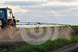 Tractor spraying pesticides on vegetable field with sprayer at spring