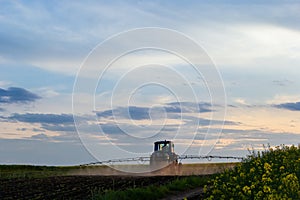 Tractor spraying pesticides on vegetable field with sprayer at spring