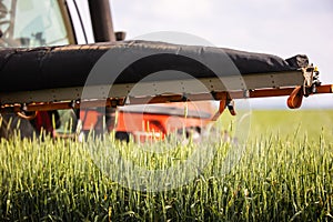 Tractor spraying pesticides wheat field