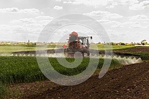 Tractor spraying pesticides wheat field