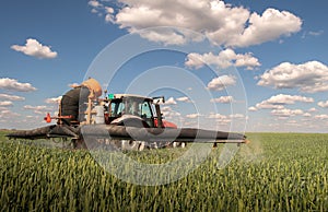 Tractor spraying pesticides wheat field