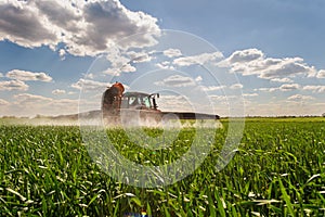 Tractor spraying pesticides wheat field