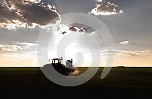 Tractor spraying soy field in sunset