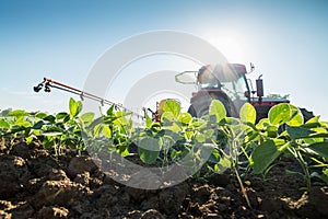 Tractor spraying soybean crops with pesticides and herbicides.