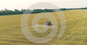 The tractor sprays the wheat fields. Spraying a field with wheat view from a drone. A tractor sprays wheat with