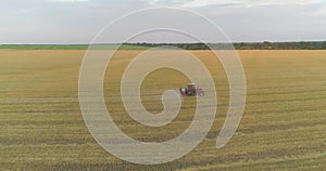 A tractor sprays wheat with herbicides. The tractor sprays the wheat fields. Spraying a field with wheat view from a