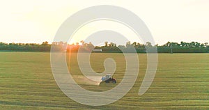 A tractor sprays wheat with herbicides. The tractor sprays the wheat fields. Spraying a field with wheat view from a