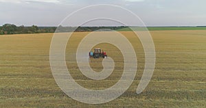 A tractor sprays wheat with herbicides. The tractor sprays the wheat fields. Spraying a field with wheat view from a