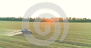 A tractor sprays wheat with herbicides. The tractor sprays the wheat fields. Spraying a field with wheat view from a