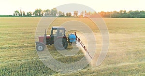 A tractor sprays wheat with herbicides. The tractor sprays the wheat fields. Spraying a field with wheat view from a