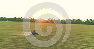 A tractor sprays wheat with herbicides. The tractor sprays the wheat fields. Spraying a field with wheat view from a