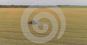 A tractor sprays wheat with herbicides. The tractor sprays the wheat fields. Spraying a field with wheat view from a