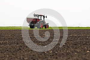 Tractor spreading artificial fertilizers in field