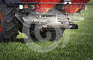 Tractor spreading artificial fertilizers in field